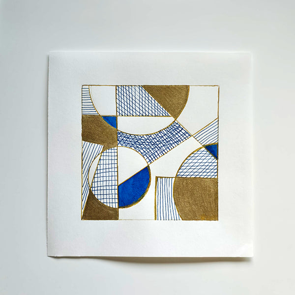 A square white art print or card featuring an abstract geometric design with blue, white, and metallic gold shapes and hatched lines, photographed against a light gray background.