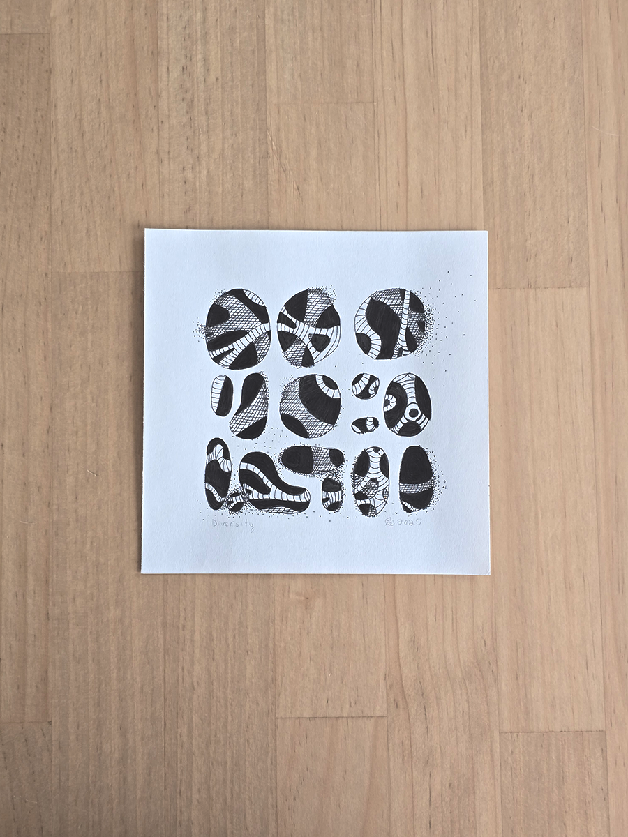 A square white art print featuring black ink abstract oval patterns, laid flat on a light wood countertop.