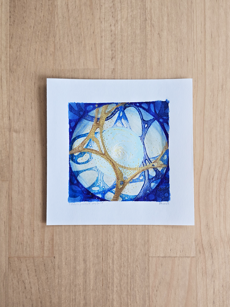 A square abstract art print featuring blue and white circular patterns with gold metallic veins, presented on a white sheet of paper over a light wood background.